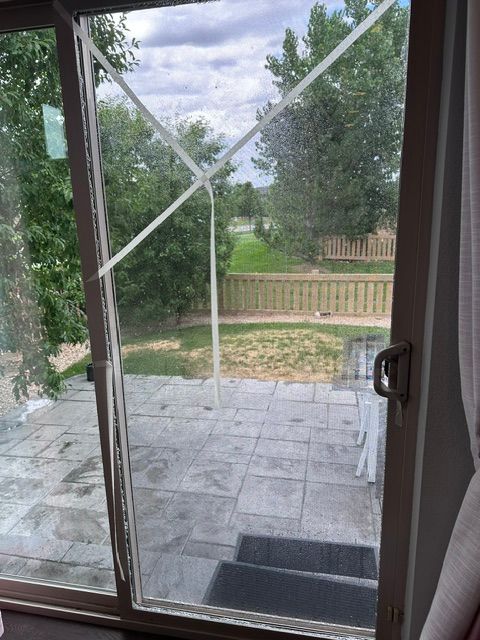 Sliding glass door with taped crack, overlooking patio, yard, and wooden fence.