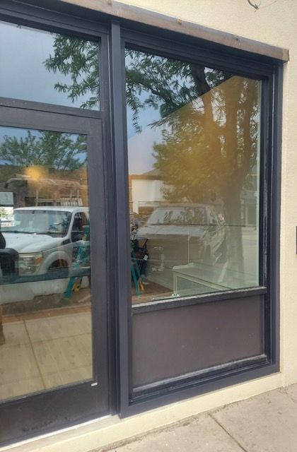 Storefront window with dark trim reflecting parked vehicles outside