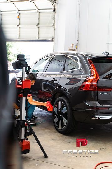 A man is cleaning the side of a car in a garage.