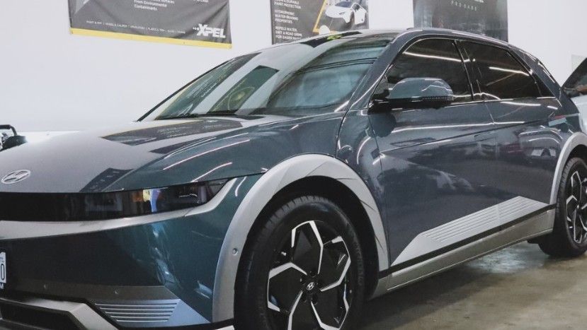Dark gray Hyundai Ioniq 5 electric SUV. Silver trim and wheels, tinted windows. Inside a shop.