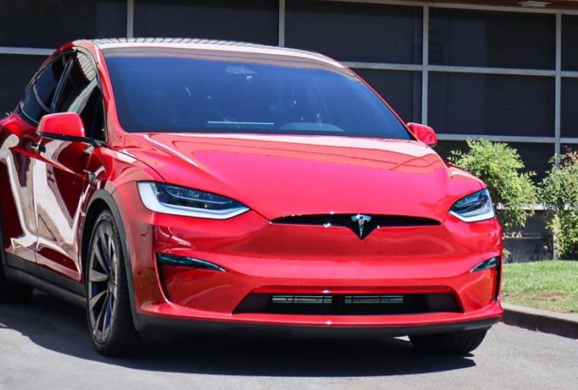 Red Tesla Model X SUV parked in front of a building.