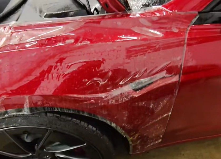 Red car fender with clear protective film applied.