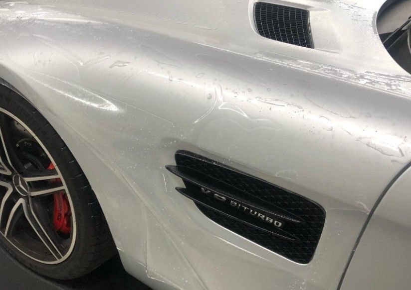 White sports car, side view, with visible air vents and a black wheel.