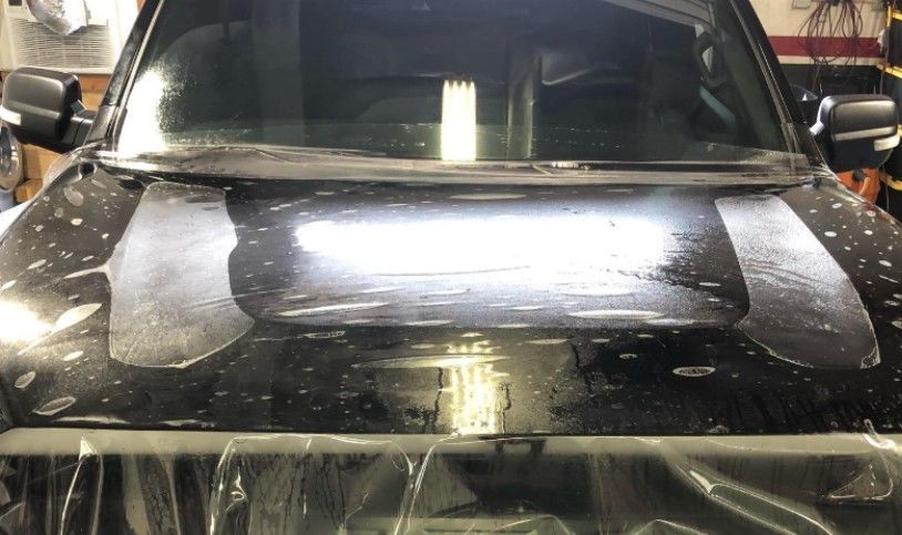 Black car hood with clear protective film applied.