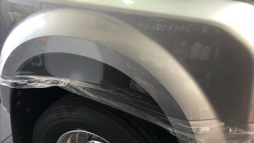 Silver truck wheel well wrapped in plastic.