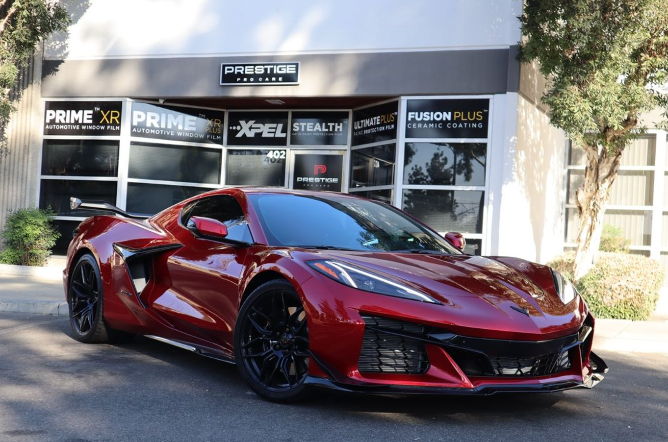 Red sports car parked in front of a building with window film signs.