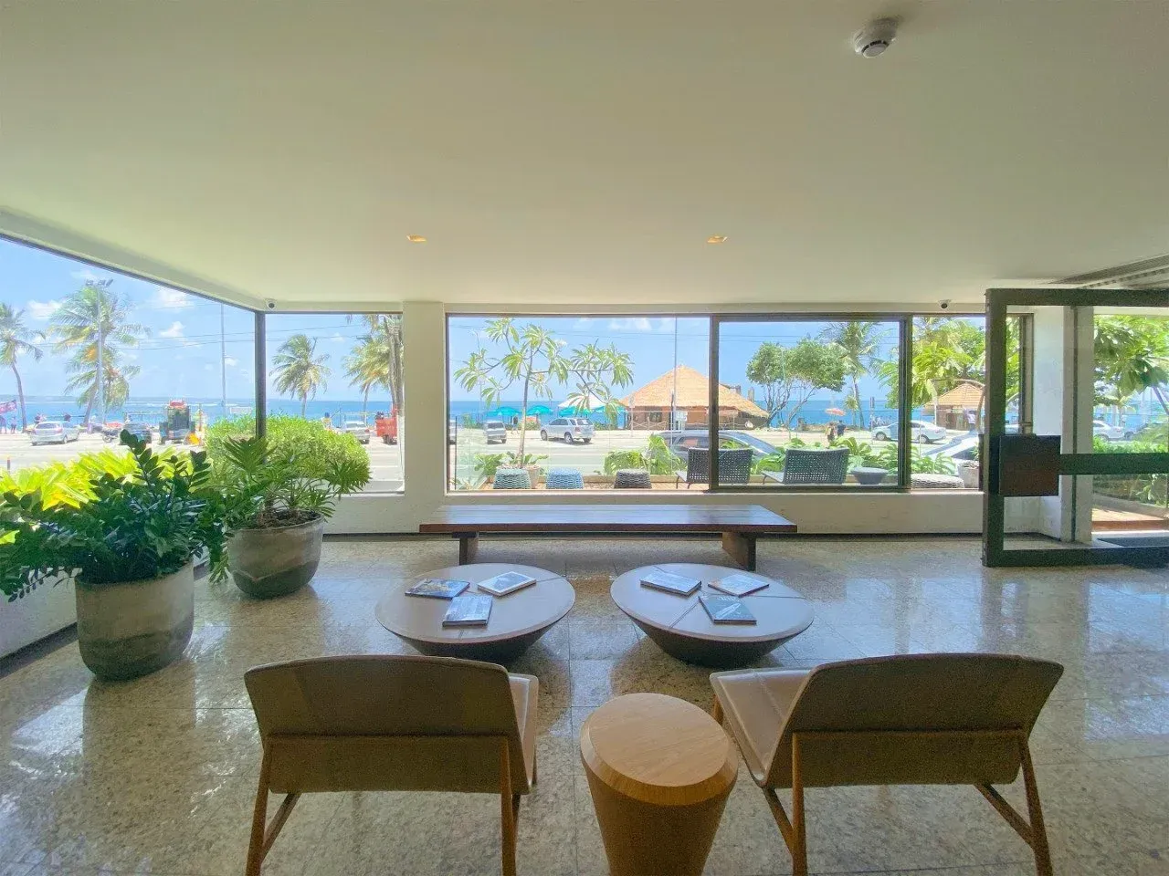 Uma sala de estar com cadeiras e mesas e vista para o oceano.