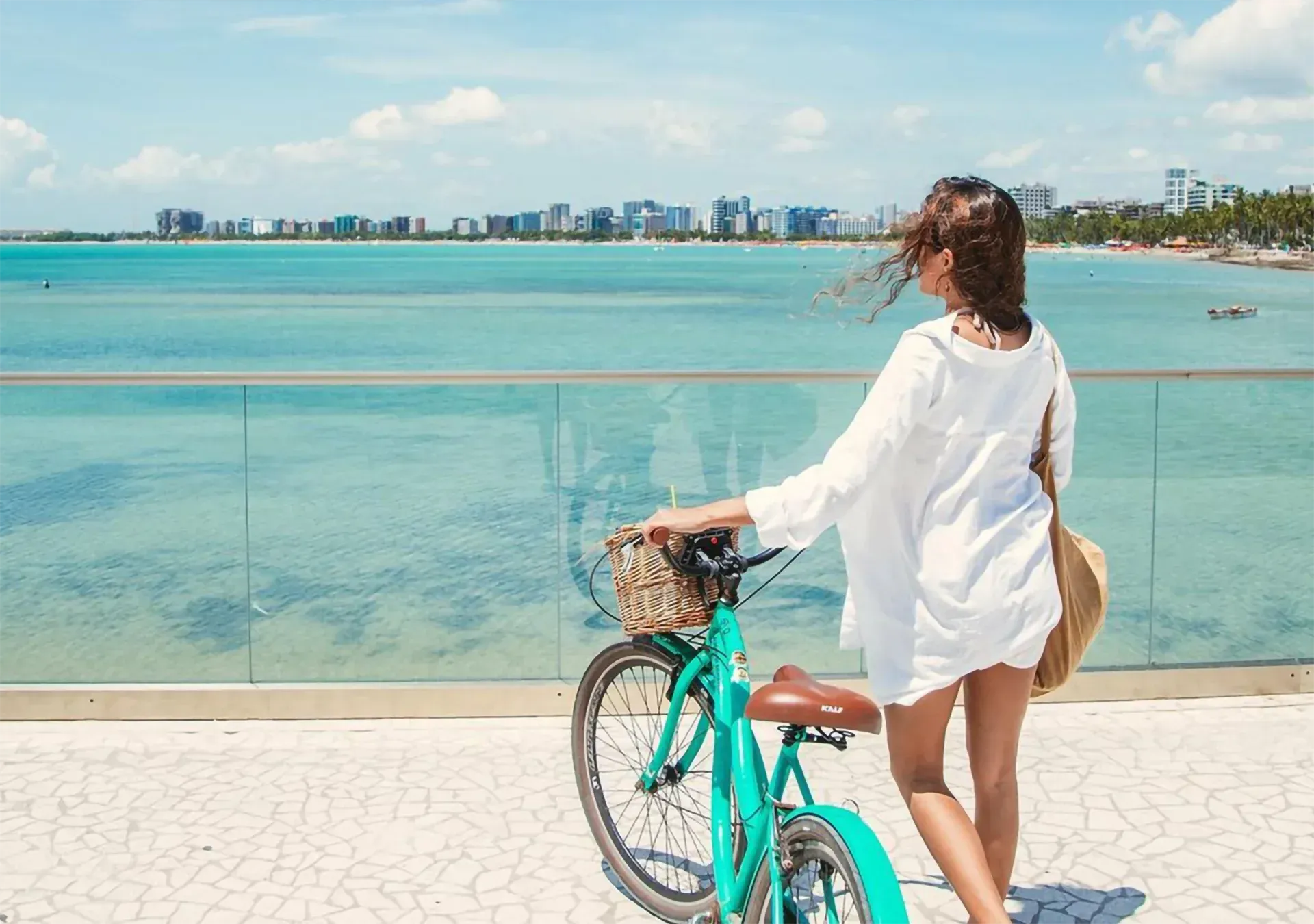 Uma mulher está parada ao lado de uma bicicleta olhando para o oceano.