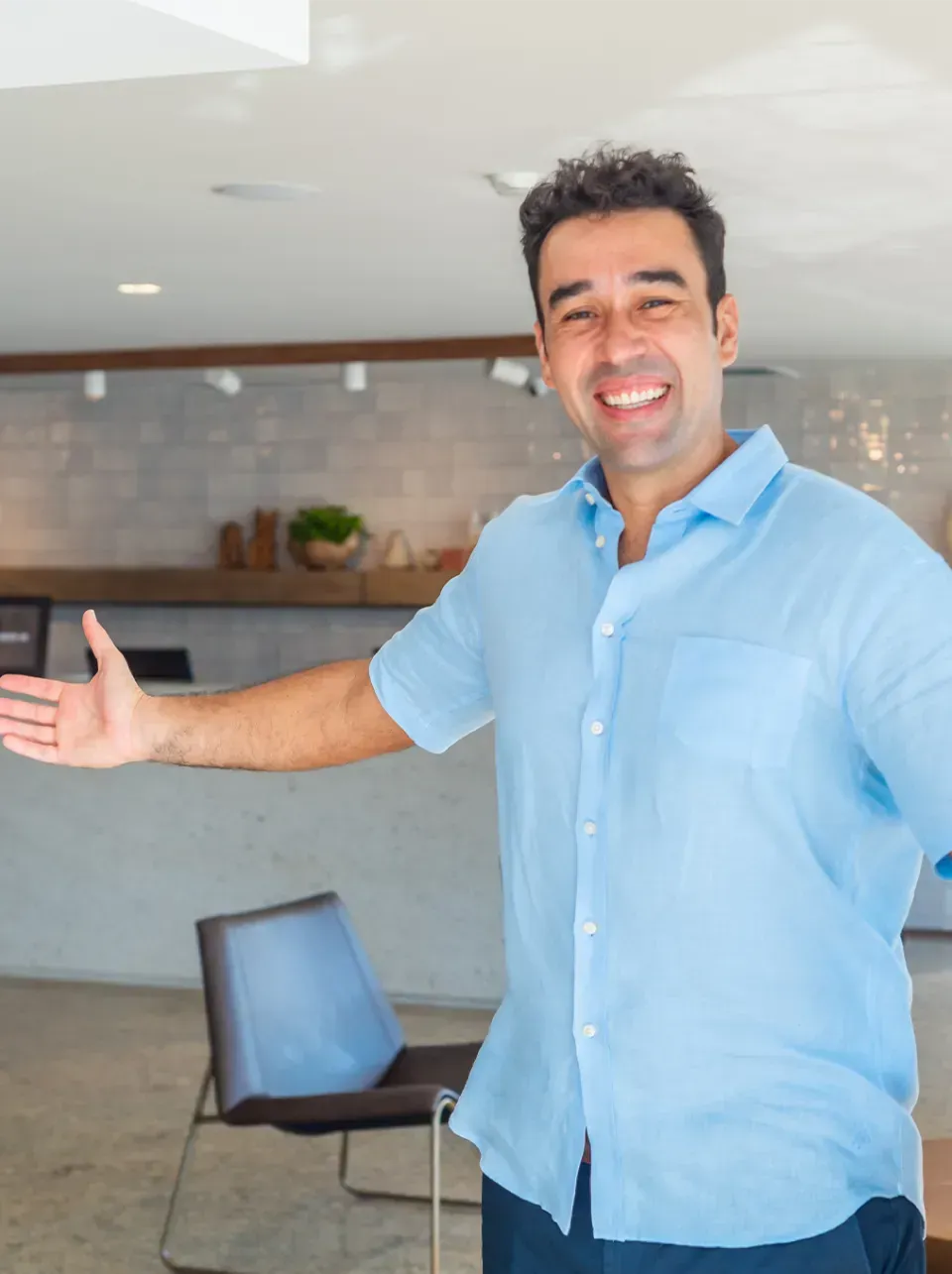 Um homem de camisa azul está sorrindo e fazendo sinal de positivo