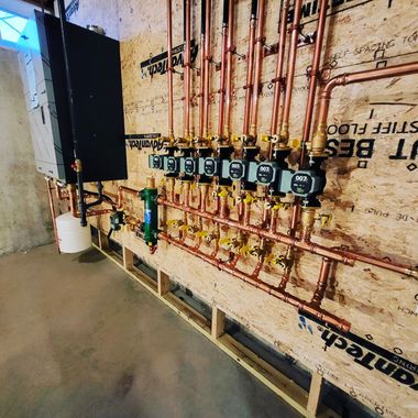 Exposed plumbing and water meters mounted on a wall in an unfinished basement area.