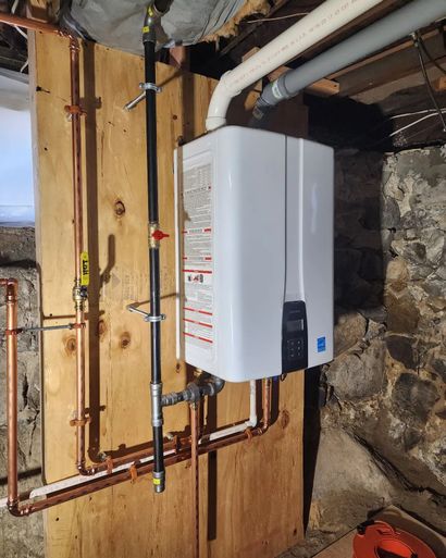 White wall-mounted boiler with copper pipes in an unfinished basement utility area