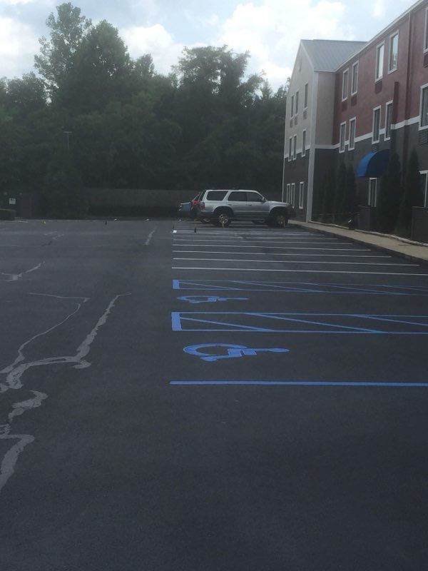 Empty parking lot with blue accessible parking markings beside a building and parked SUV