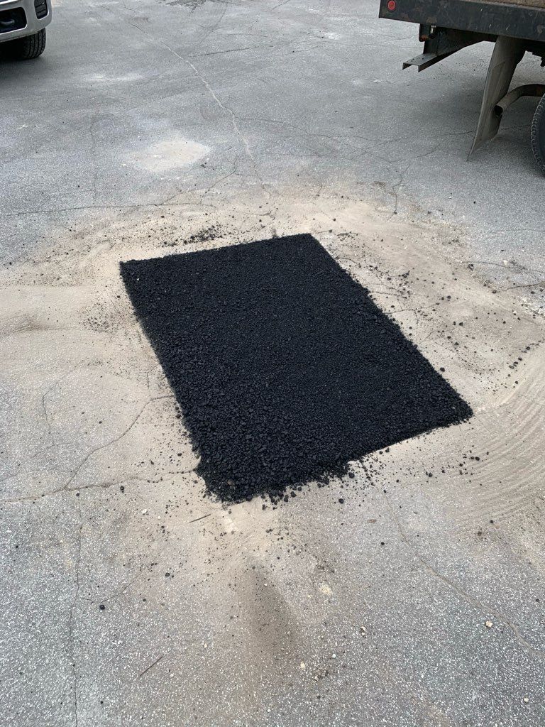 Black rectangular mat on a rough concrete surface outdoors.