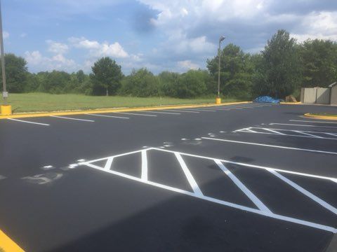 Empty parking lot with fresh white striping and yellow bollards under a partly cloudy sky