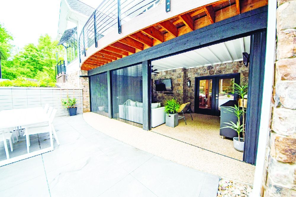 Outdoor patio with retractable screen doors, stone walls, and a view of a deck above.