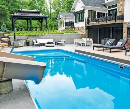 Outdoor pool area with slide, gazebo, seating, and a multi-story house.