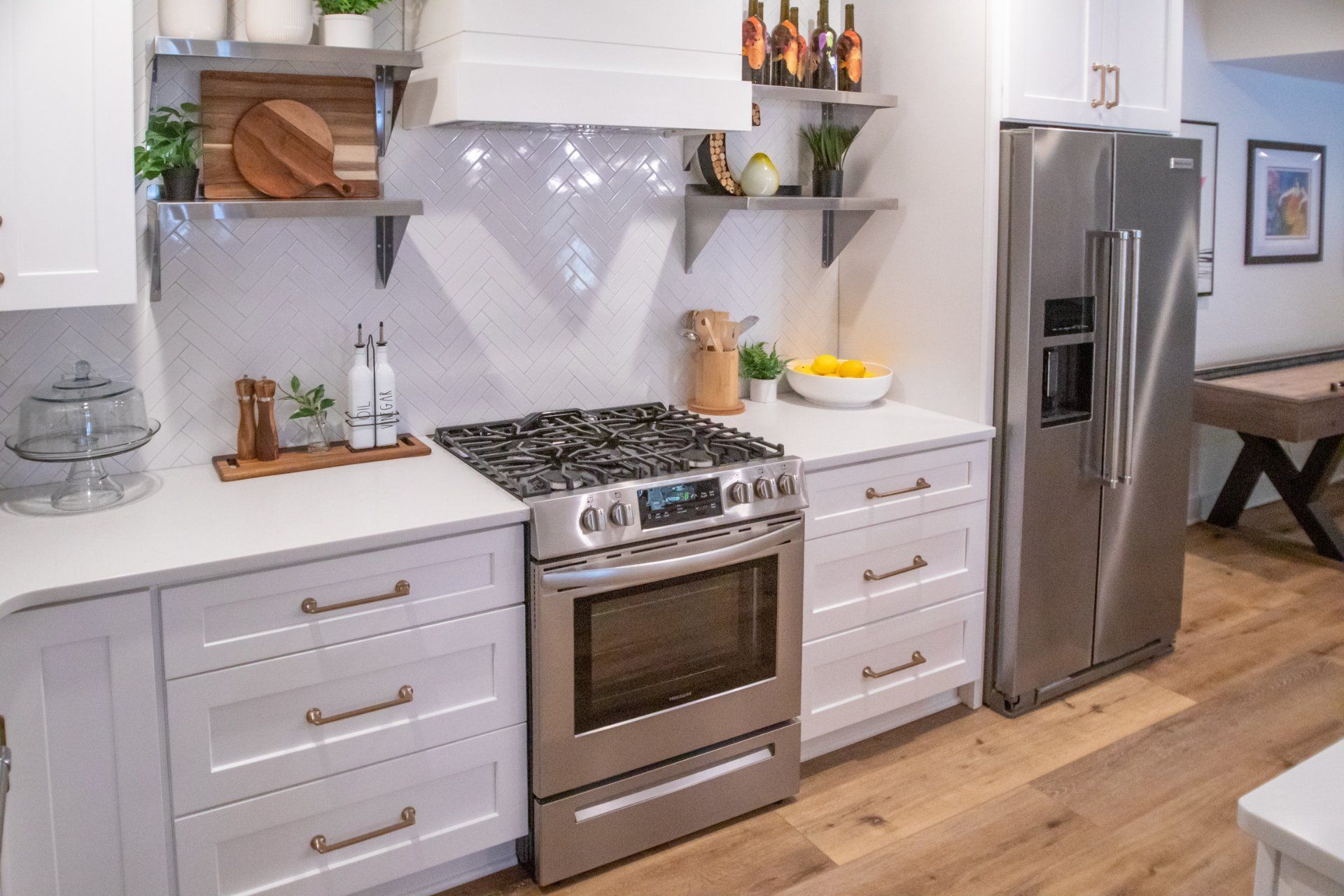 Modern kitchen with stainless steel appliances, white cabinets, and wood flooring.