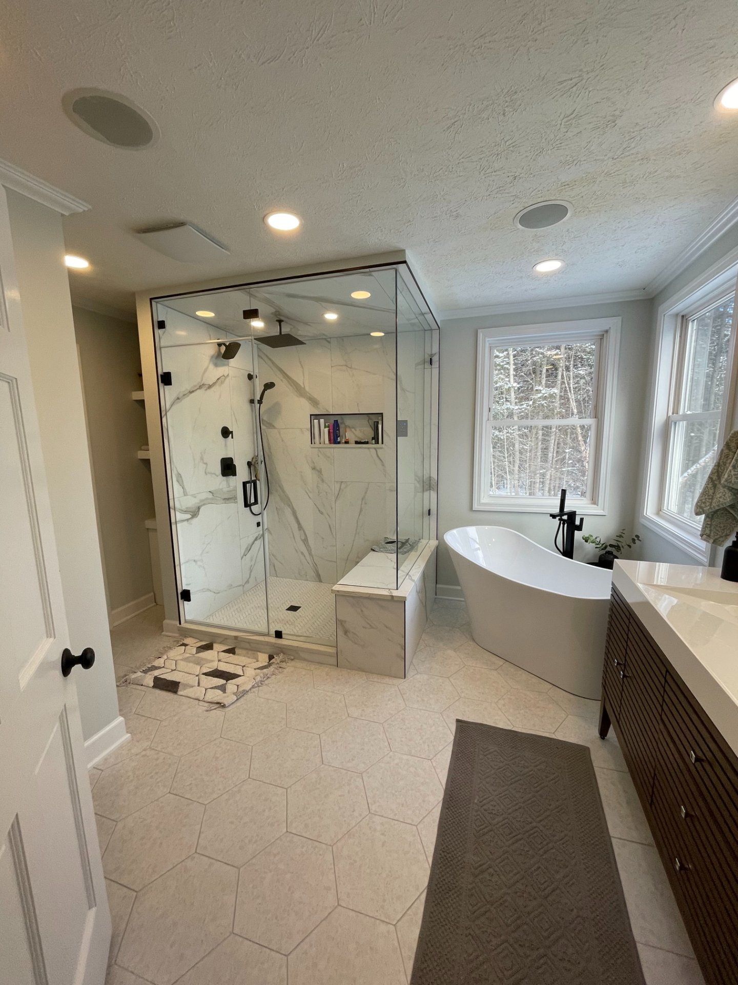 Luxurious modern bathroom with a glass shower, soaking tub, and vanity.