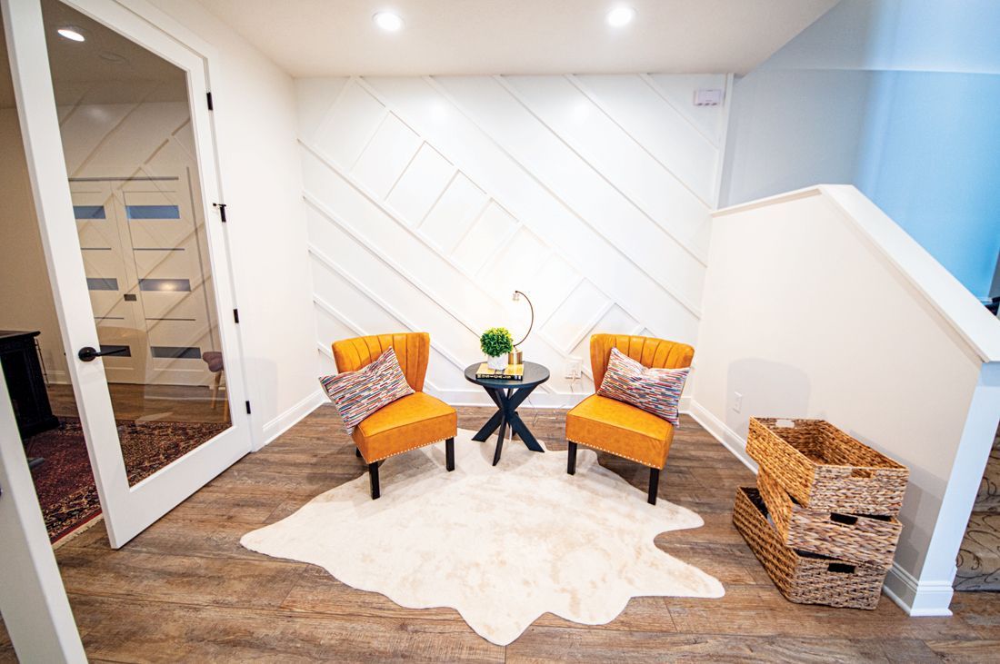 Cozy reading nook with orange chairs, small table, and white textured wall.