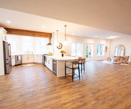 Spacious, open-concept kitchen with white cabinets, large island with seating, and wood-look flooring.