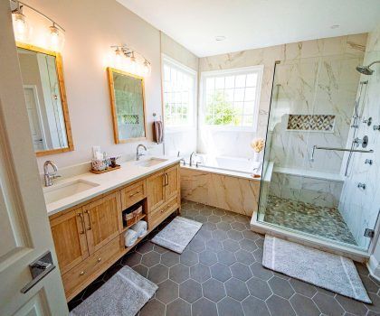 Bathroom with double sink vanity, soaking tub, and walk-in shower. Gray hexagon tile flooring.