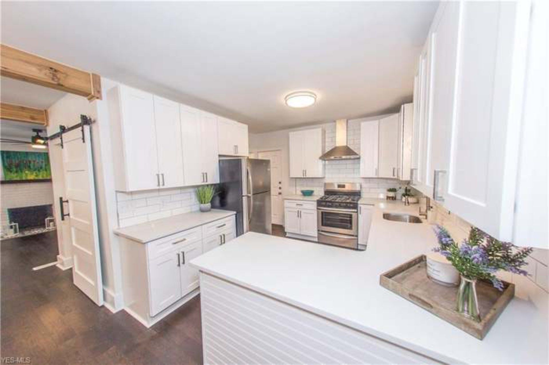 White kitchen with stainless steel appliances, white cabinets, and wooden accents.