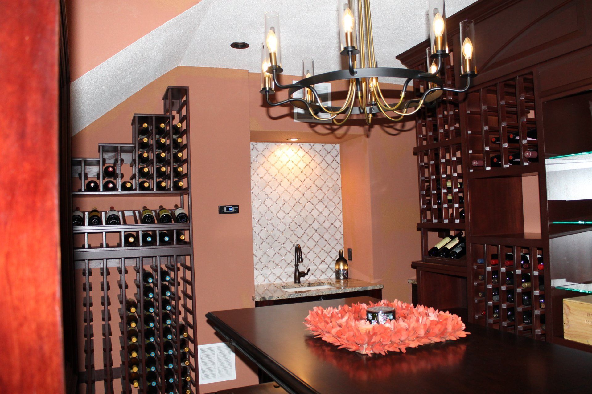 Wine cellar with dark wood racks, a small bar, and a chandelier.