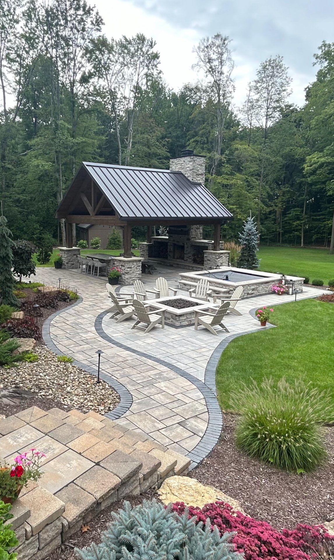 Stone patio with a pavilion, fire pit, and landscaped yard.