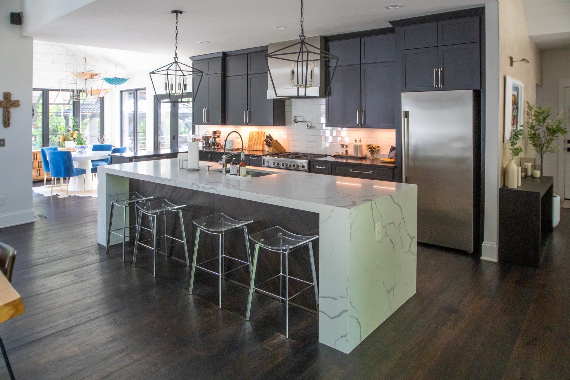 Modern kitchen with dark cabinets, stainless steel appliances, white island with stools.