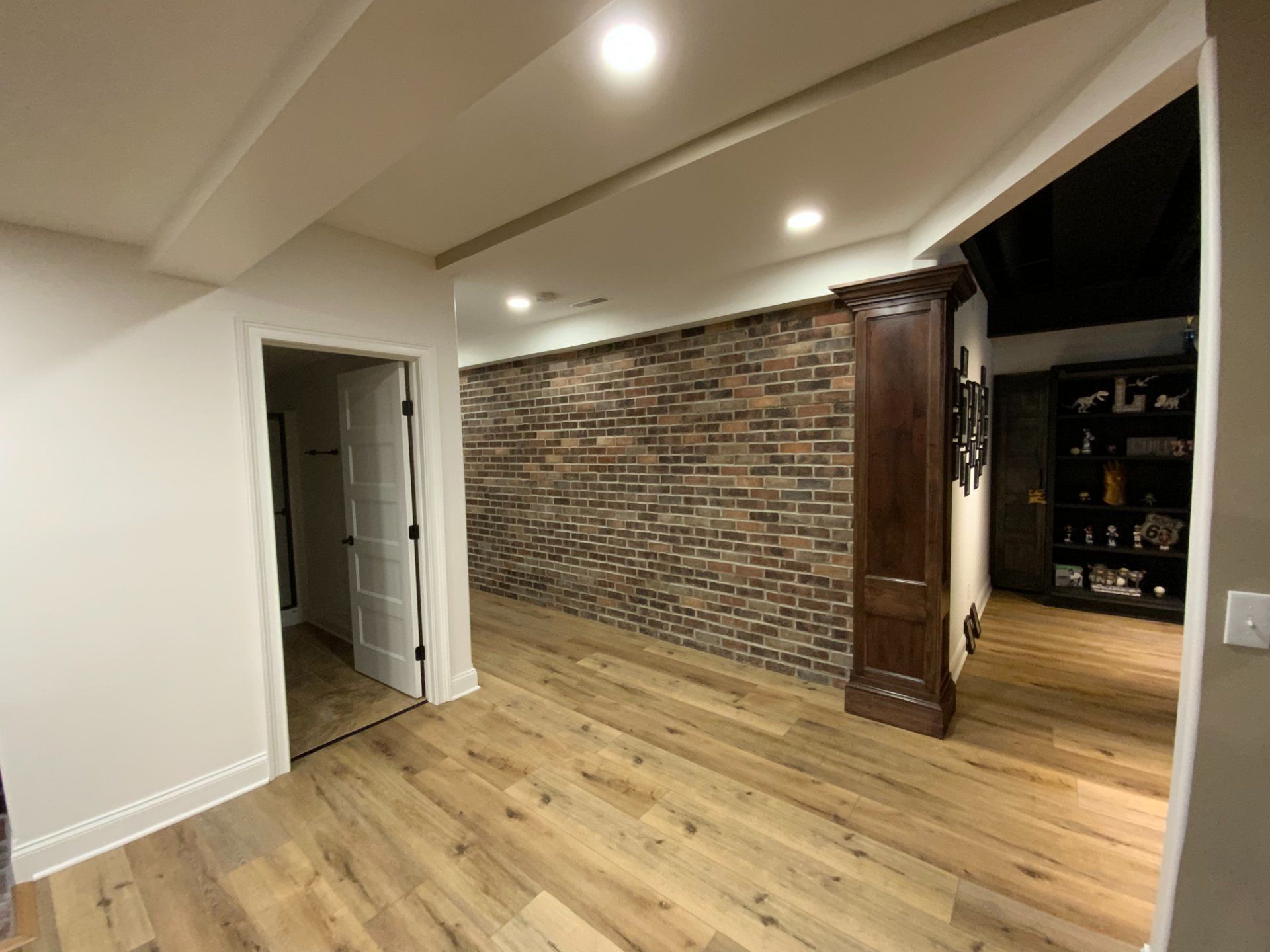 Room with wood floor, brick wall, built-in cabinet, and open doorway.