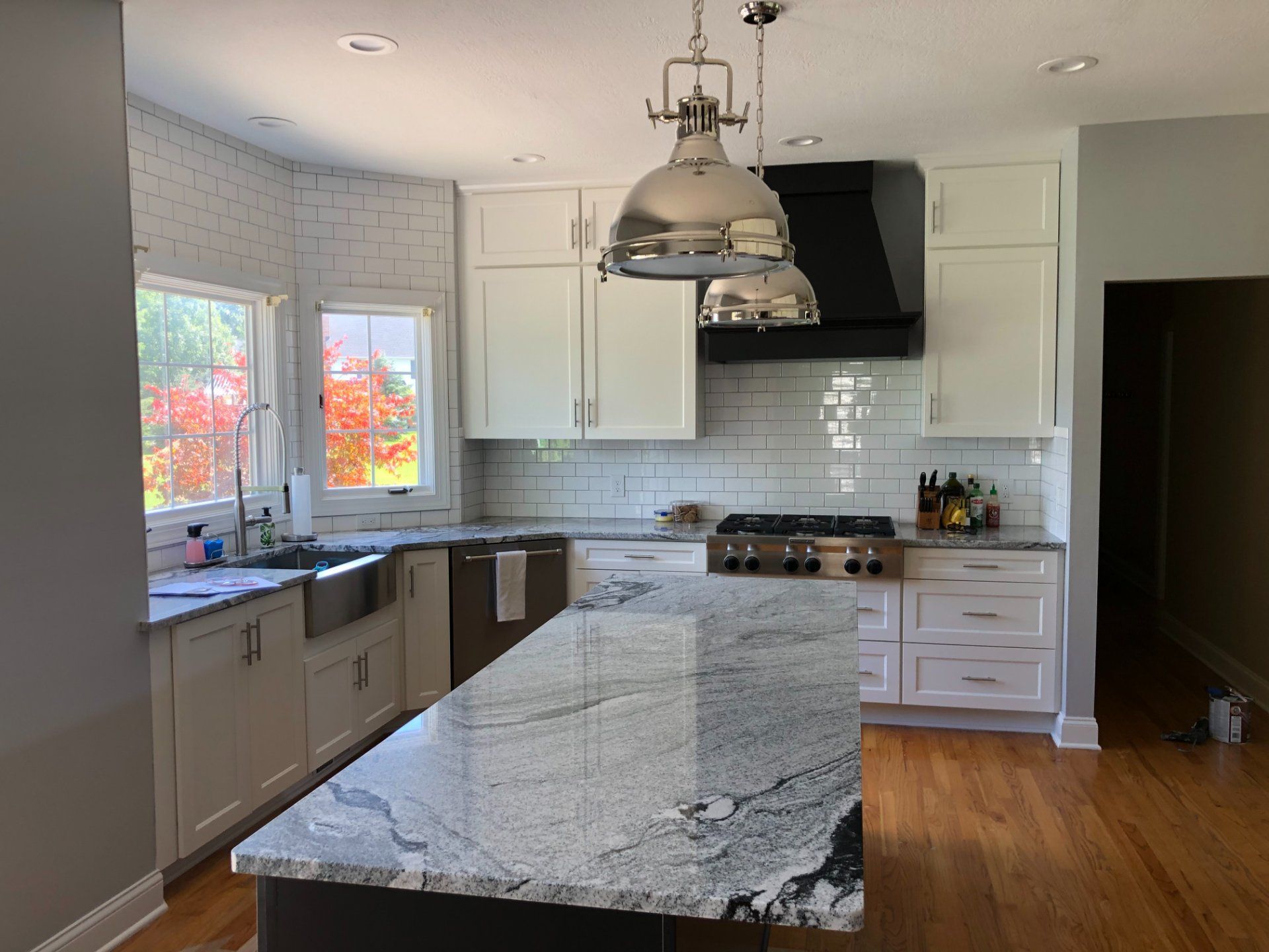 Kitchen with white cabinets, granite island, stainless steel appliances, and wooden floors.