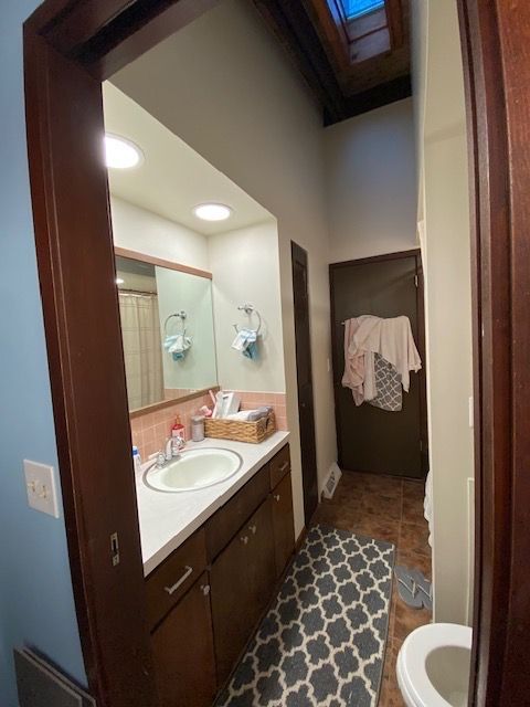 Bathroom interior with vanity, mirror, toilet, and patterned rug.