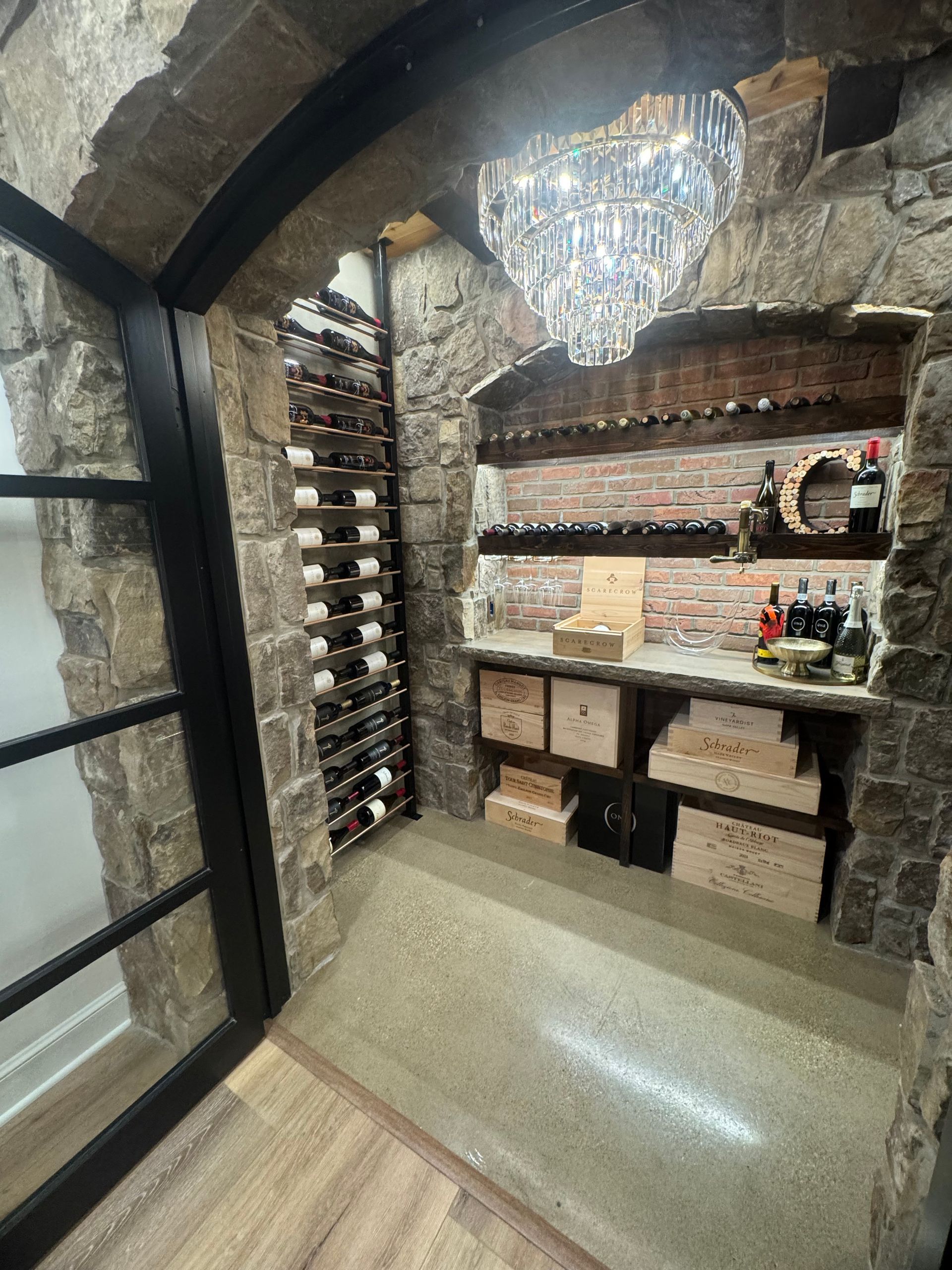 Wine cellar with stone walls, metal wine racks, and a decorative light fixture.