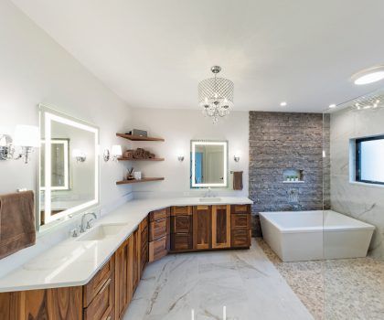 Spacious modern bathroom with wooden cabinets, white countertops, a freestanding tub, and textured accent wall.