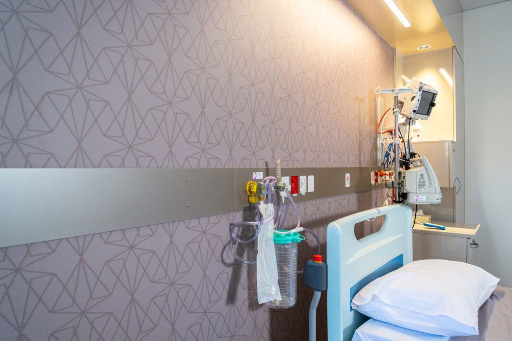 A hospital room with a bed and a monitor on the wall.