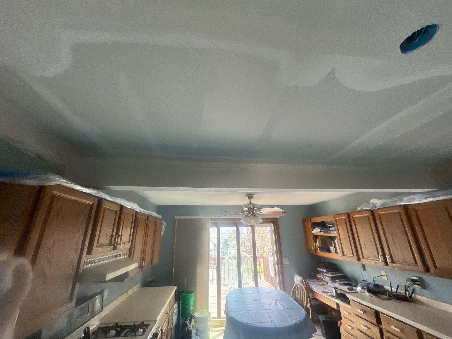 A kitchen with wooden cabinets , a table and a ceiling fan.