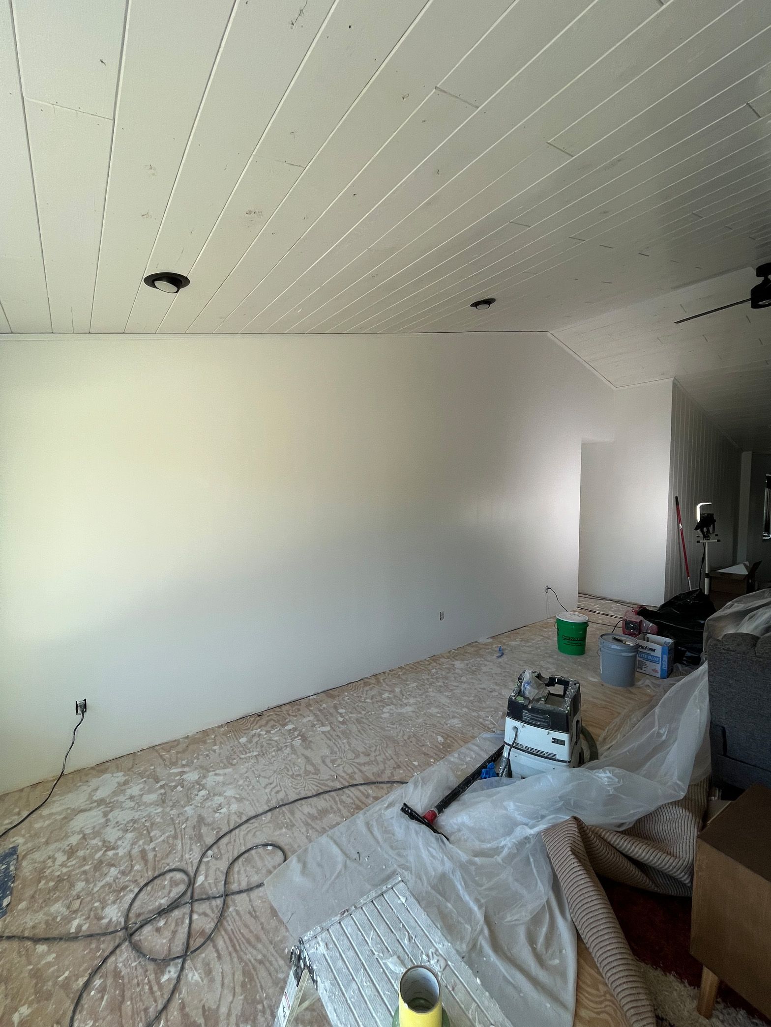 A large room with white walls and a ceiling that is being painted.