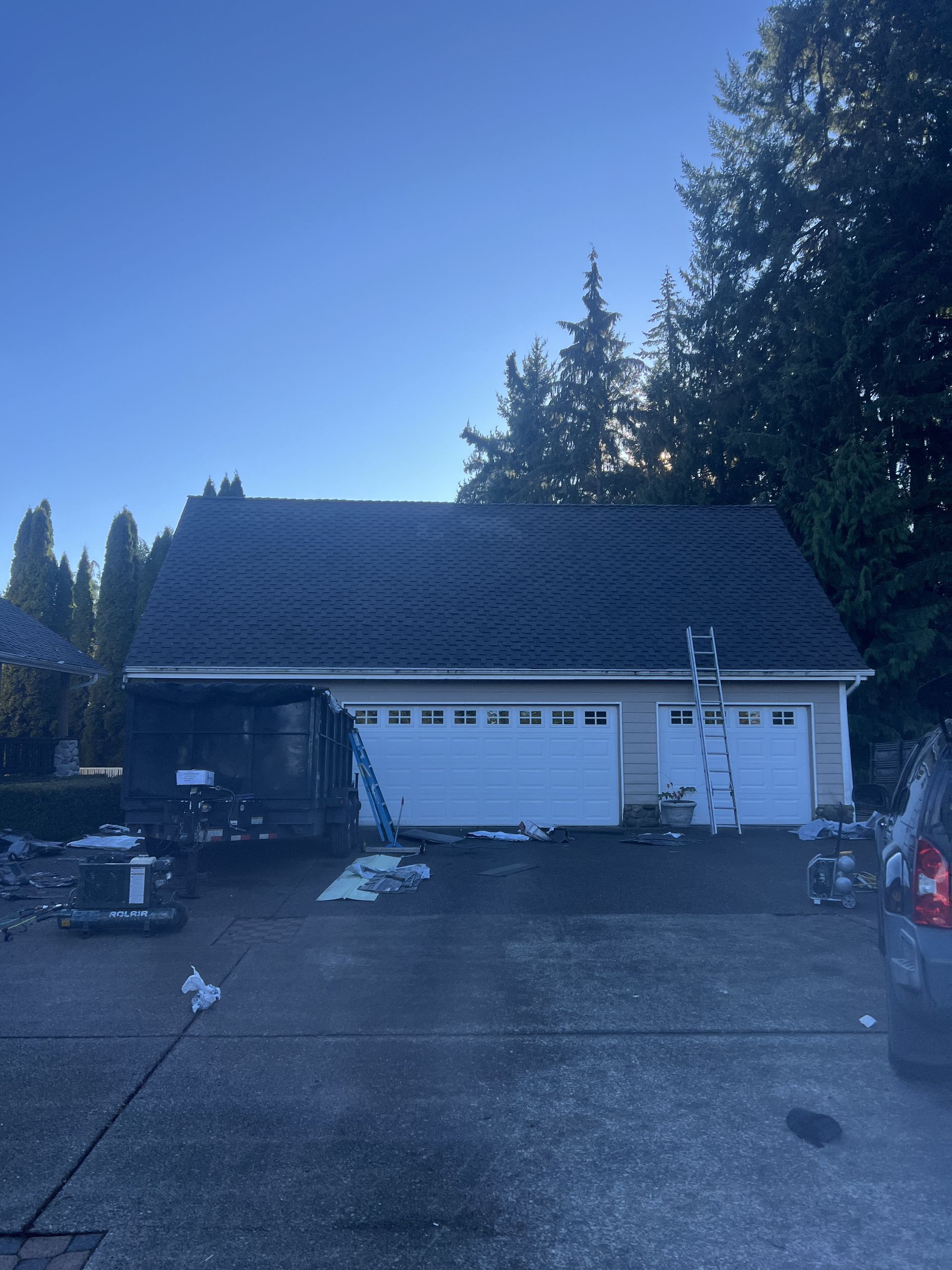Garage with fire damage on the left side, two garage doors, and a ladder propped against the roof in Lakewood, WA.