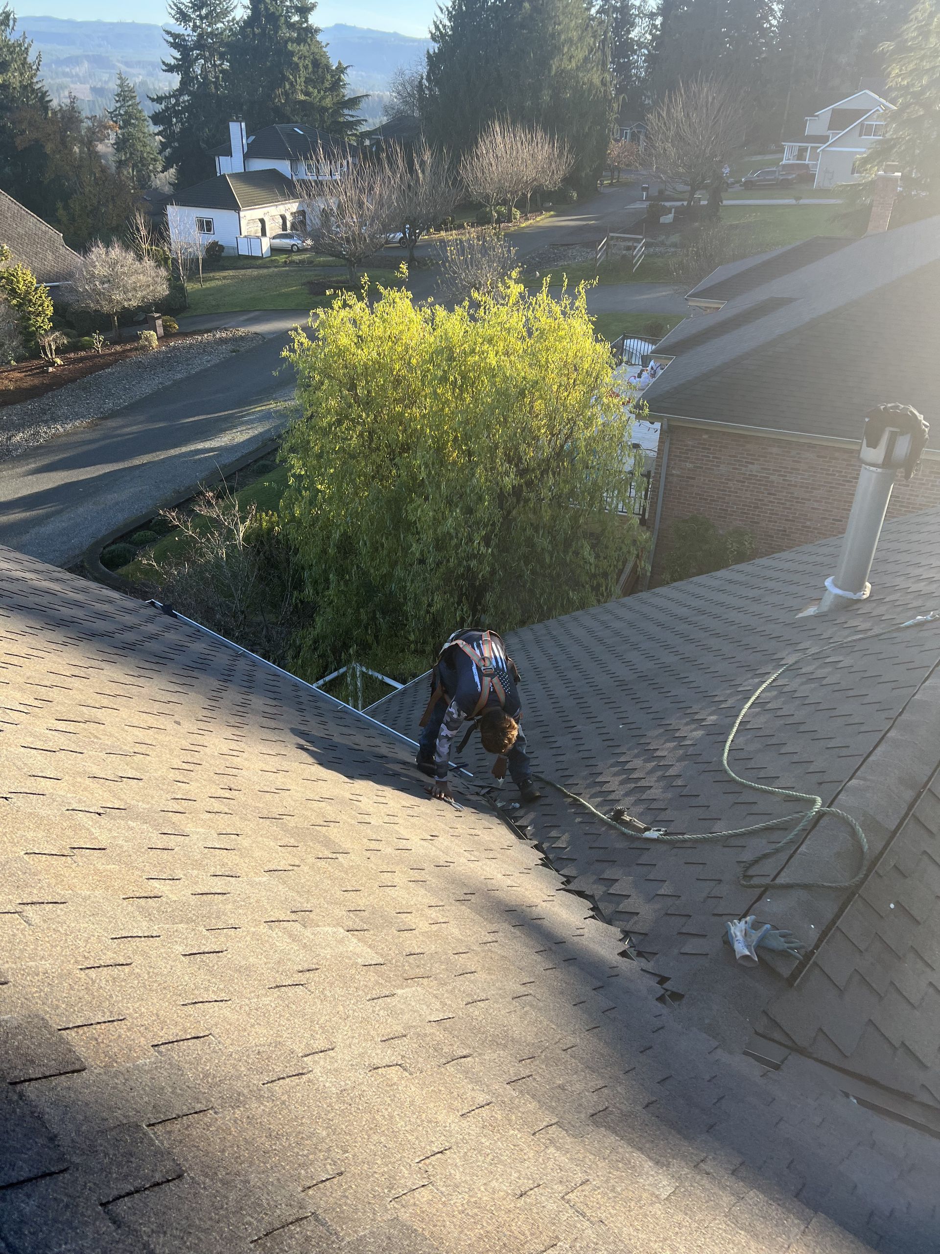Person working on a rooftop, secured by a safety line by Team Roofing NW in Bonney Lake, WA.