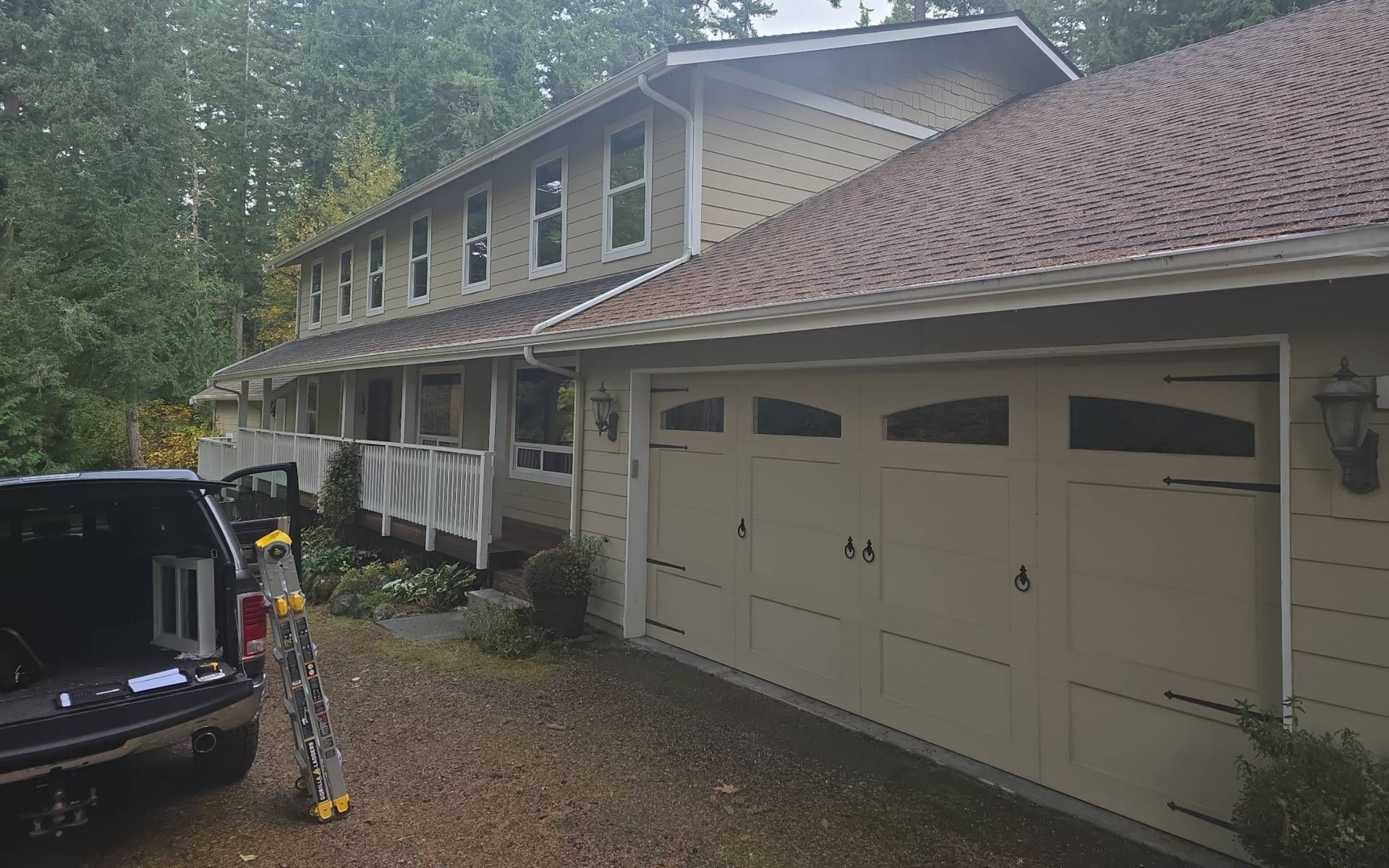 Beige two-story house with brown roof and attached garage; truck parked in driveway.
