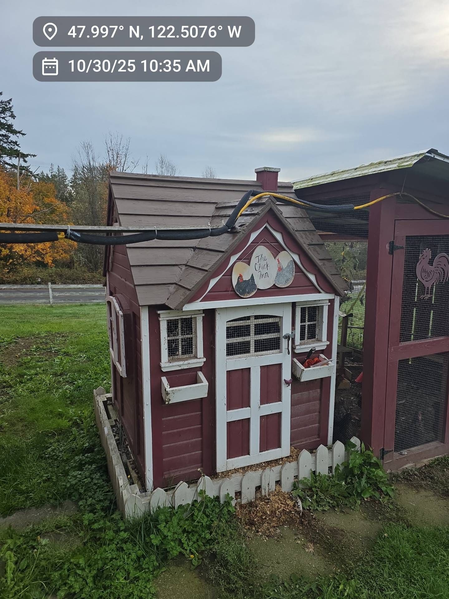 Small red playhouse with white trim, a decorative fence, and a chicken coop.