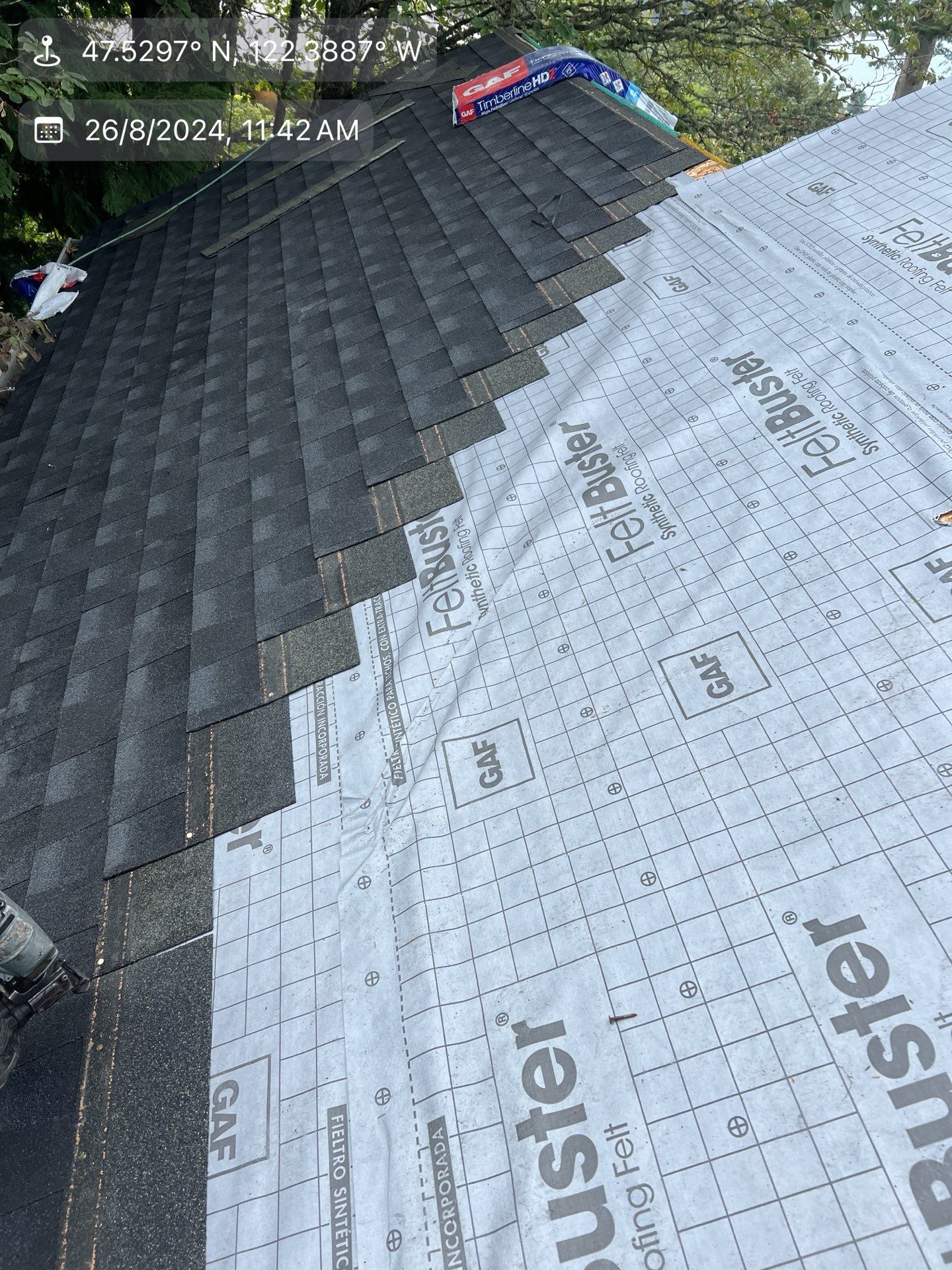 Roof with shingles being installed; gray shingles cover half, other half shows underlayment.