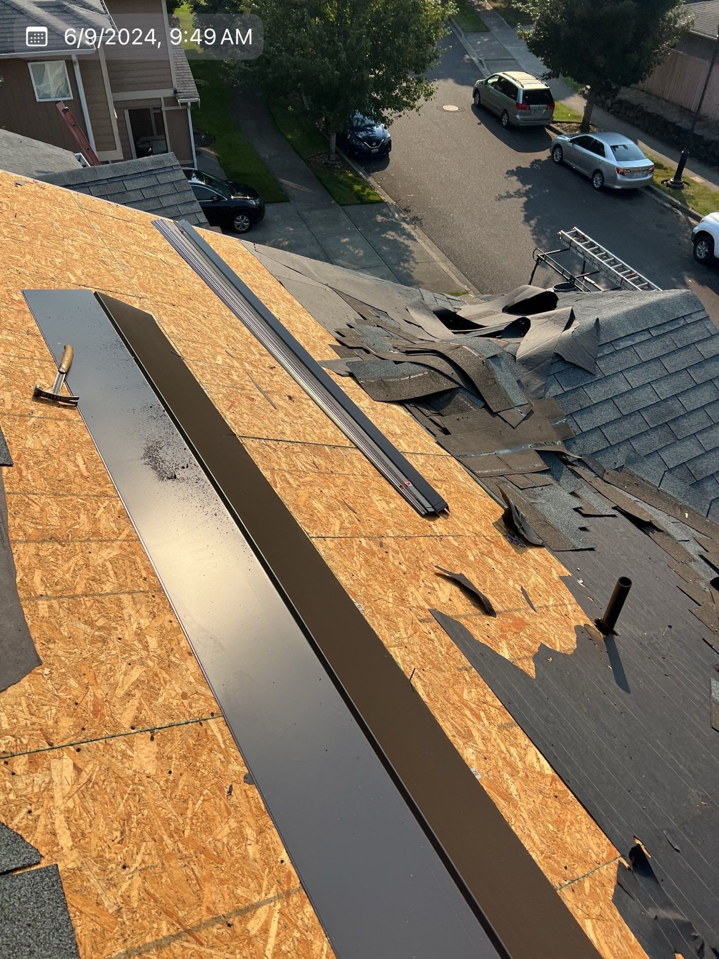 Roof repair in progress; exposed plywood and shingles. Black metal flashing installed; hammer present.