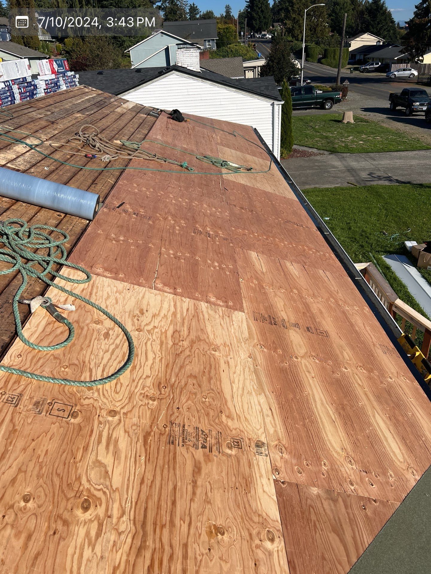 Roof under construction with plywood and rope visible. Daytime, exterior shot.