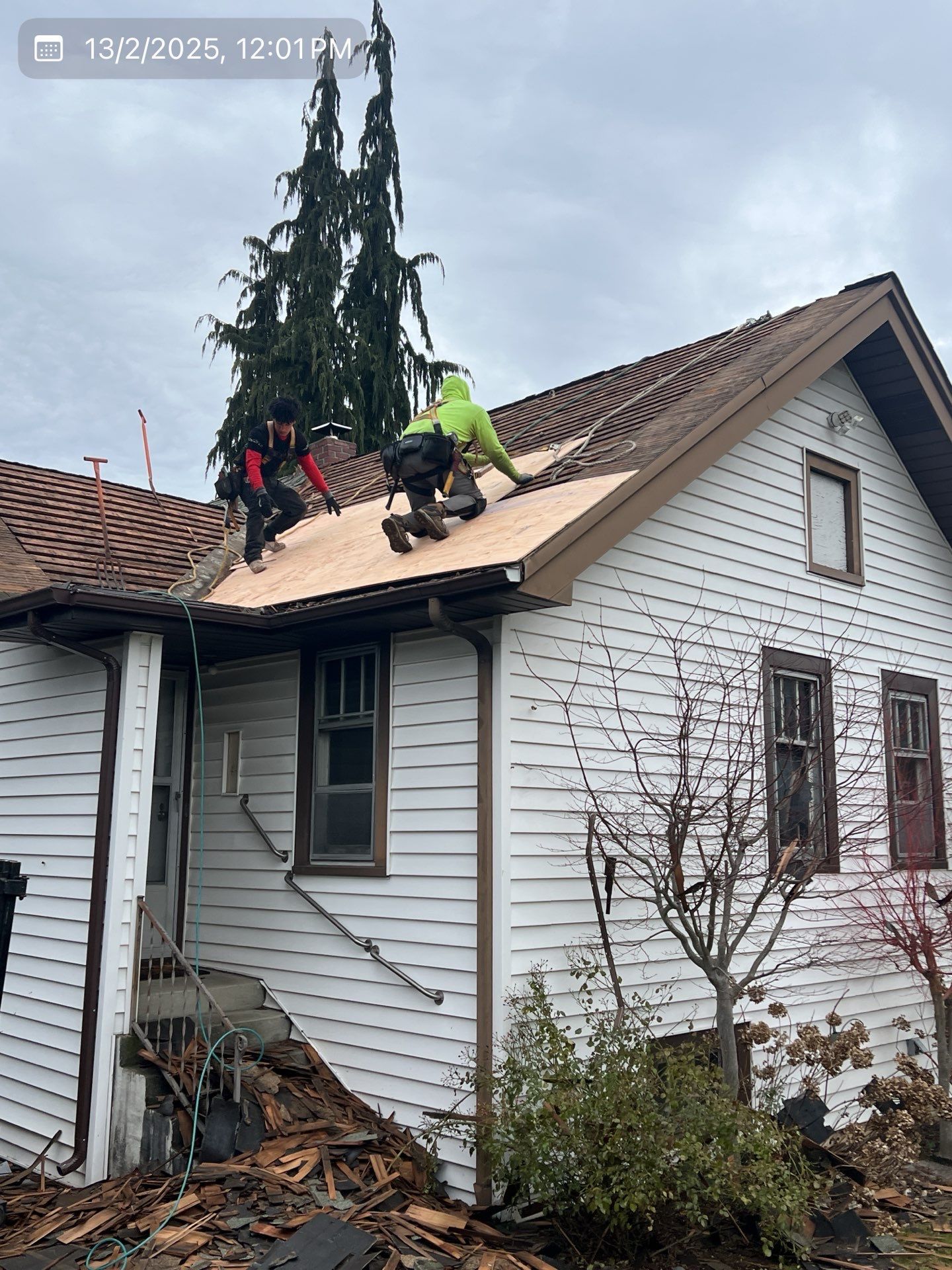 Roofers working on a house, replacing part of the roof. Cloudy sky.