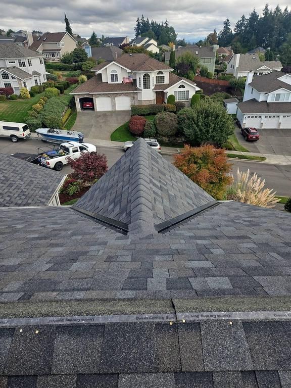 Overhead view of a house roof with a GAF  gray asphalt shingle, neighborhood in the background.