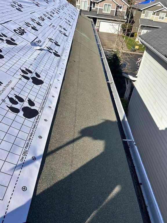 A roofing project in progress, showing new shingles installed alongside the exposed underlayment.