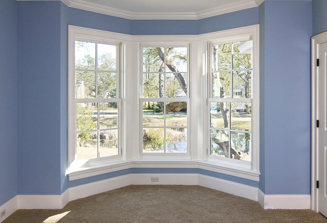Empty room with blue walls and a bay window letting in daylight