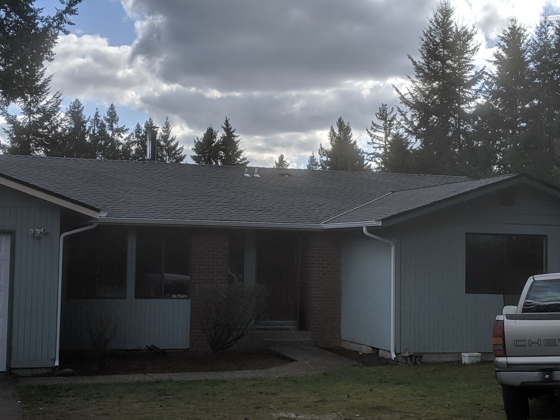 Blue house with GAF dark roof and white trim under a cloudy sky.