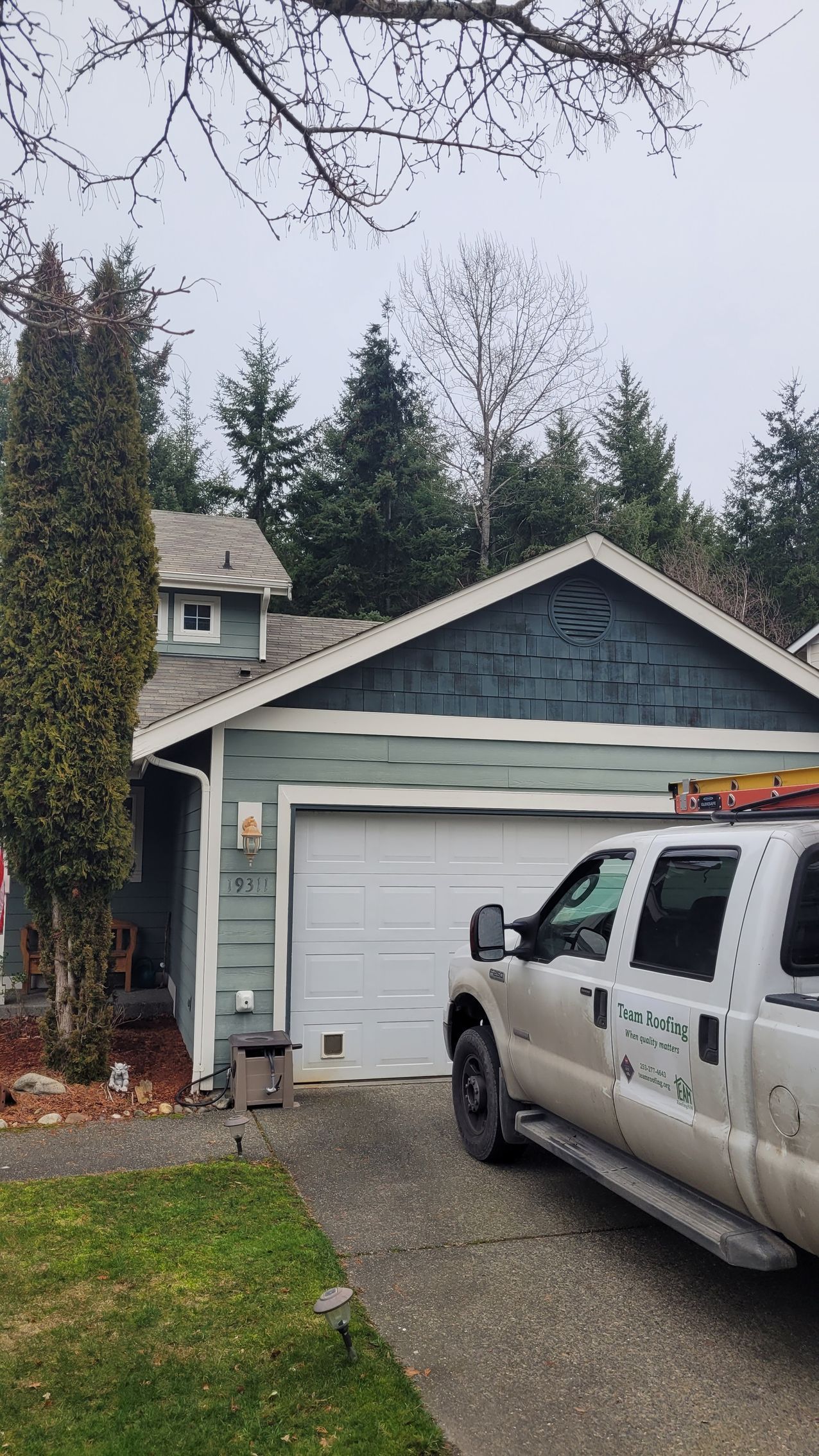 Blue house with white garage door; service truck parked in front.